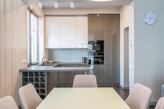 Modern kitchen and dining area with white cabinets, gray backsplash, and a table with chairs
