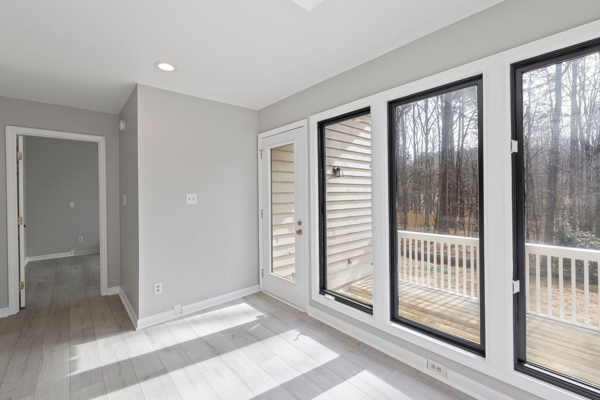 Bright empty room with gray walls, white trim, and large sliding glass doors to a deck.
