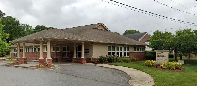 A large brick building with a porch and a sign in front of it.