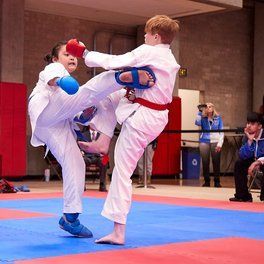 A man and a boy are practicing karate on a blue mat.