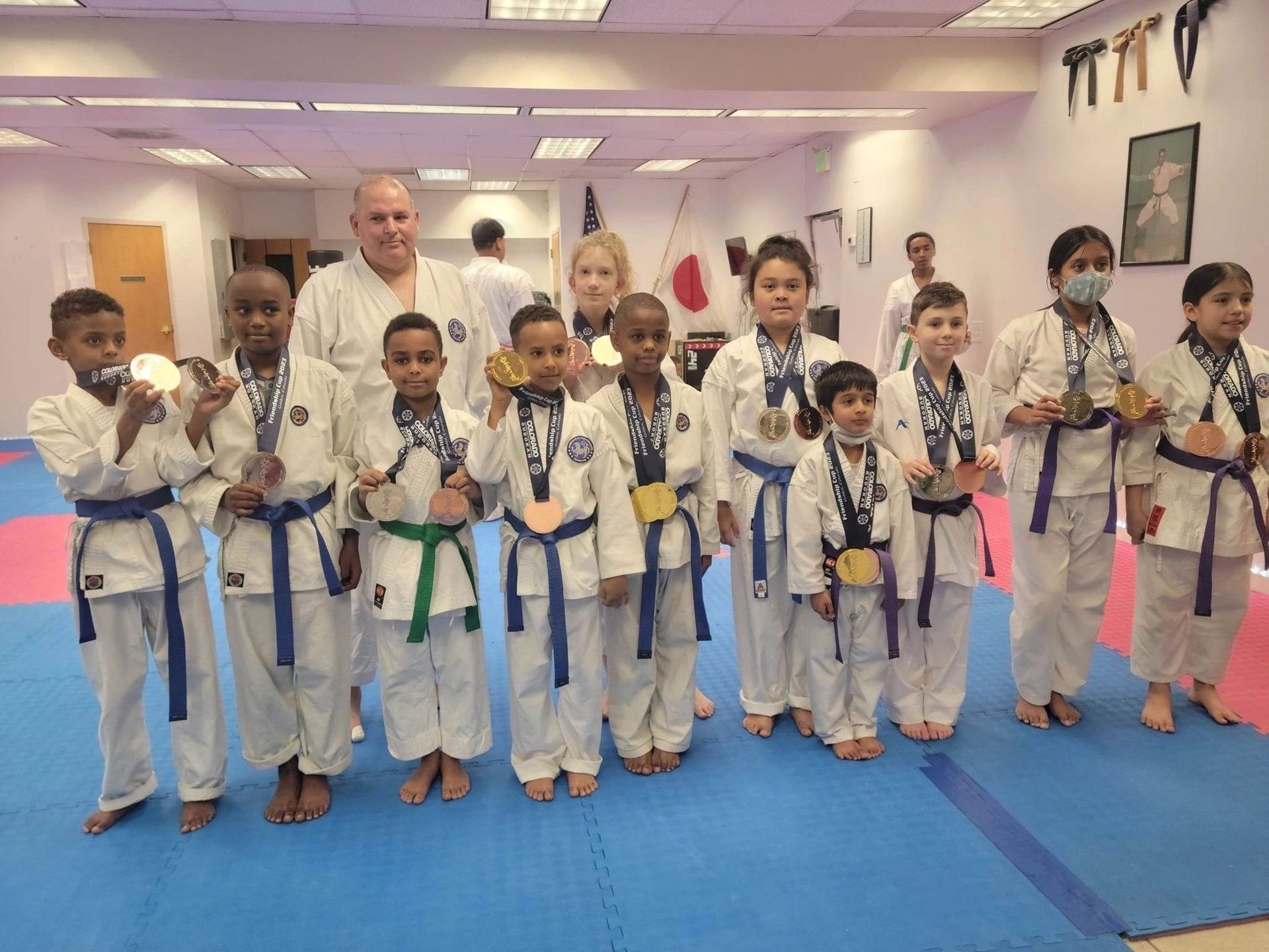 A group of children in karate uniforms are posing for a picture in a gym.
