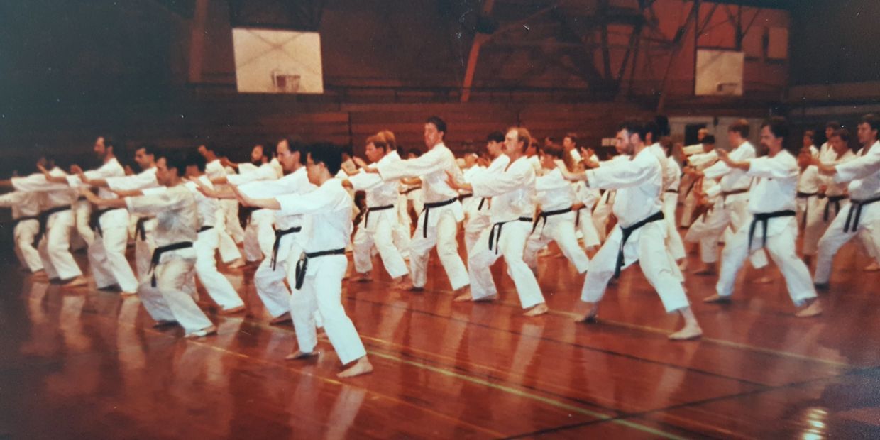 A group of people are practicing karate in a gym.