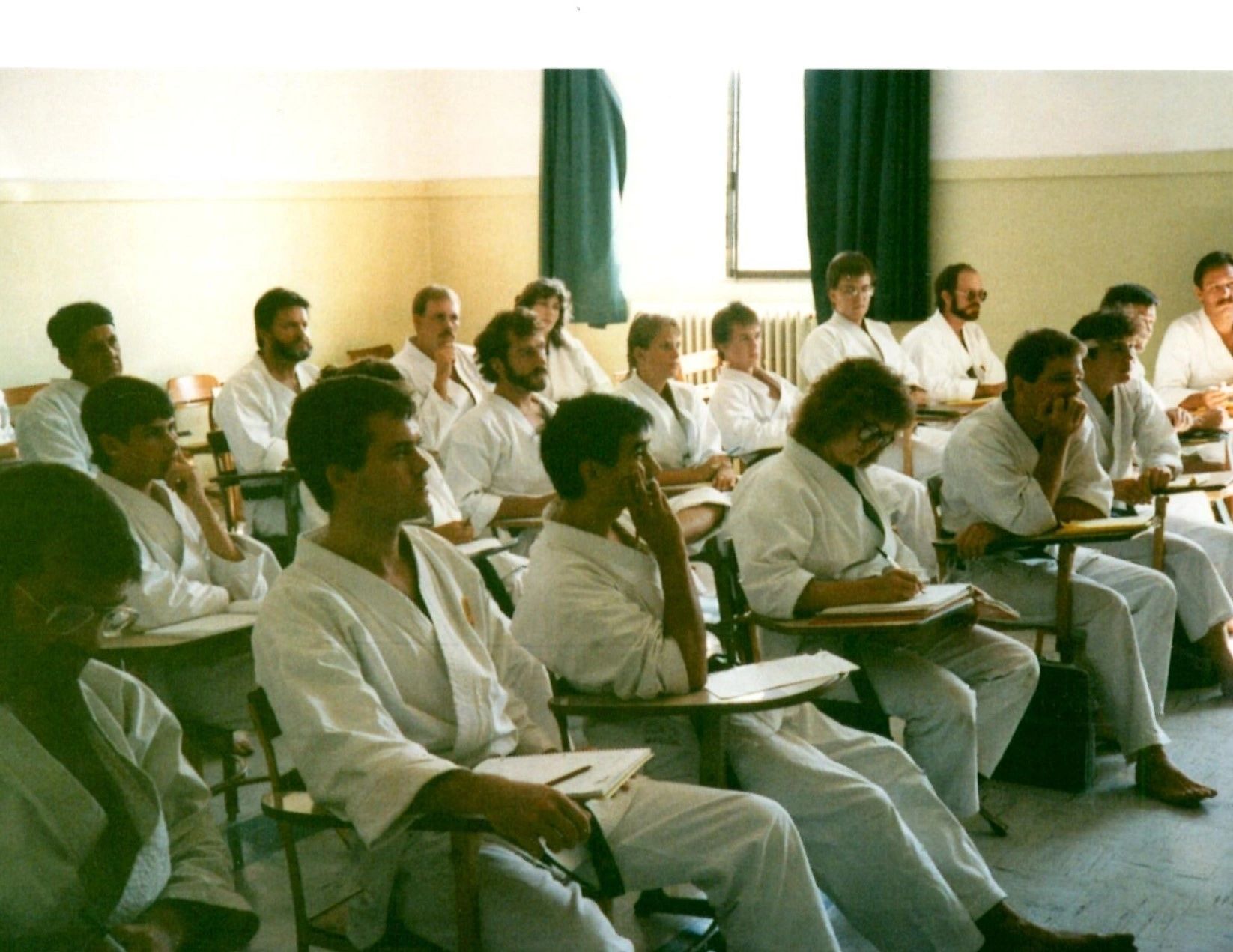 A group of people are sitting in a classroom wearing white