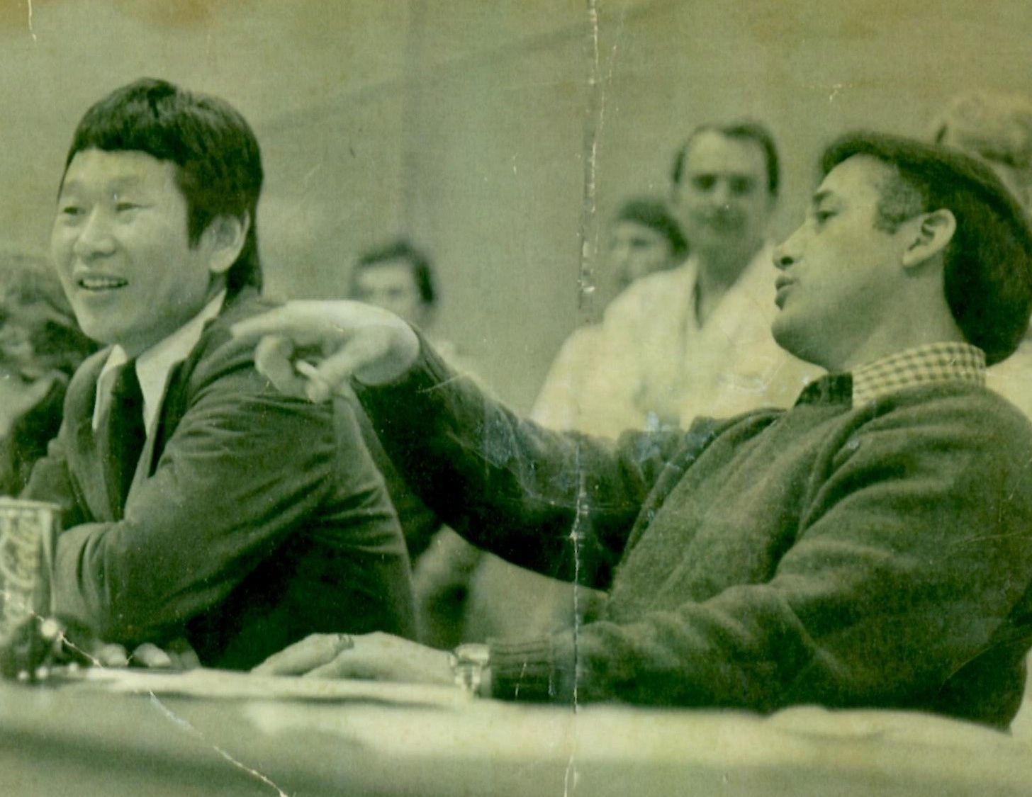 Two men are sitting at a table in a black and white photo.