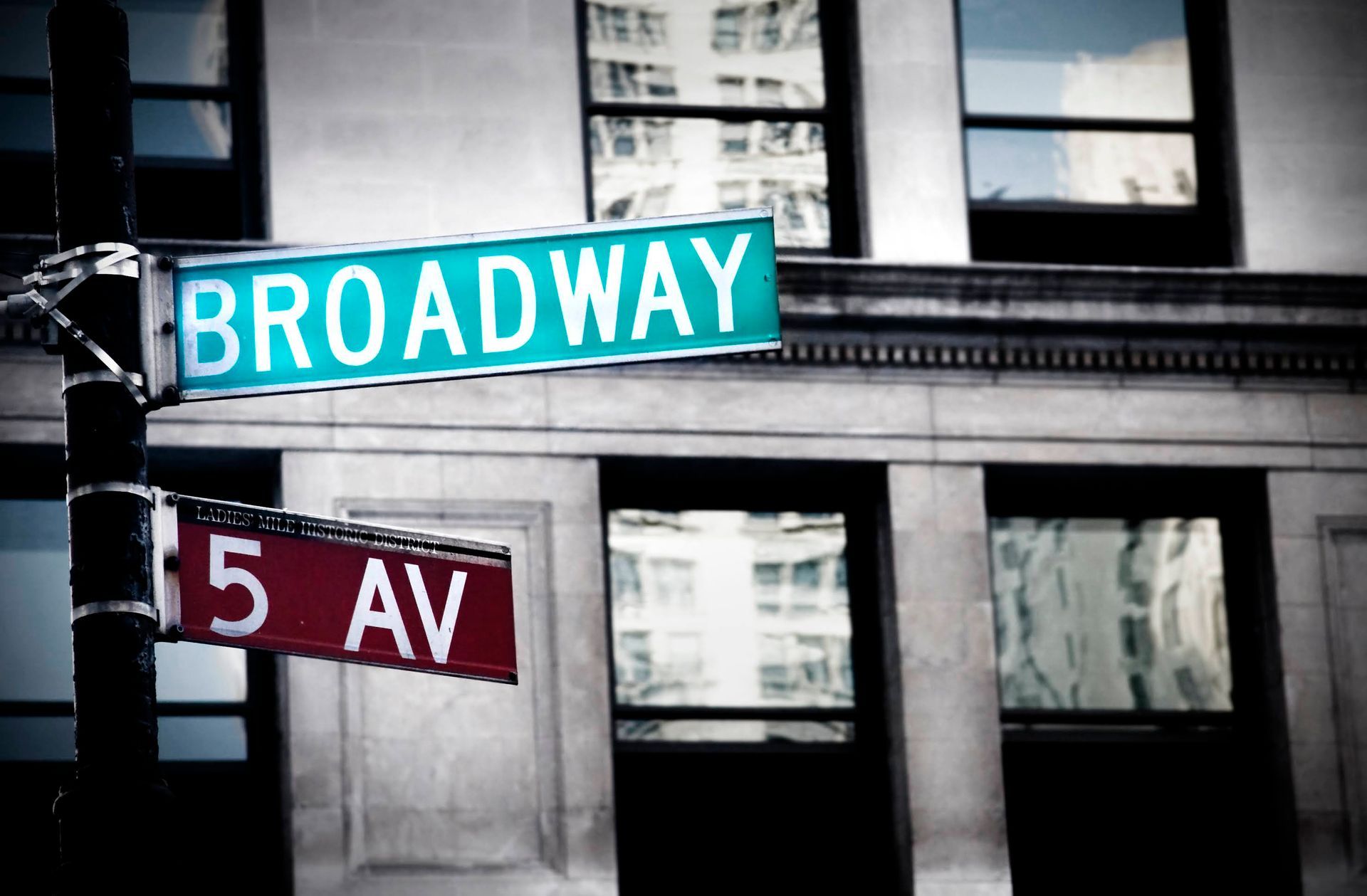 An image of a street in New York featuring a signpost indicating two different directions: Broadway and 5 AV.