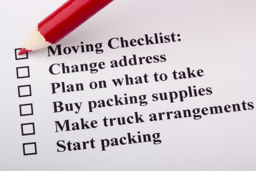 A moving checklist featuring a red pencil ticking off boxes such as change address, packing supplies, and truck arrangements. 