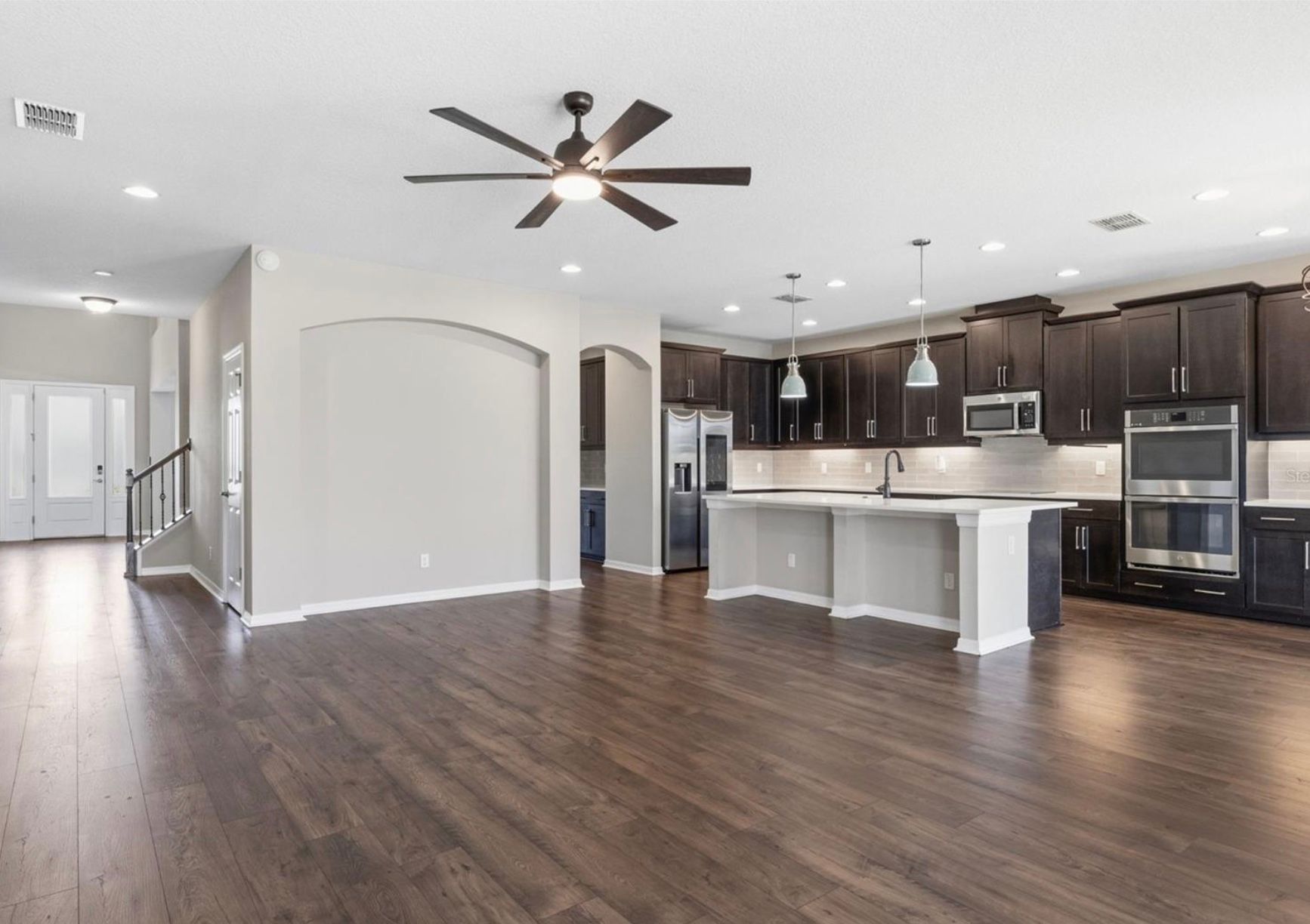 Open-concept kitchen and living area with dark wood floors, dark cabinets, and a kitchen island.