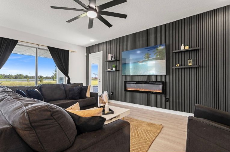 Living room with dark sectional, black accent wall with TV, and fireplace.
