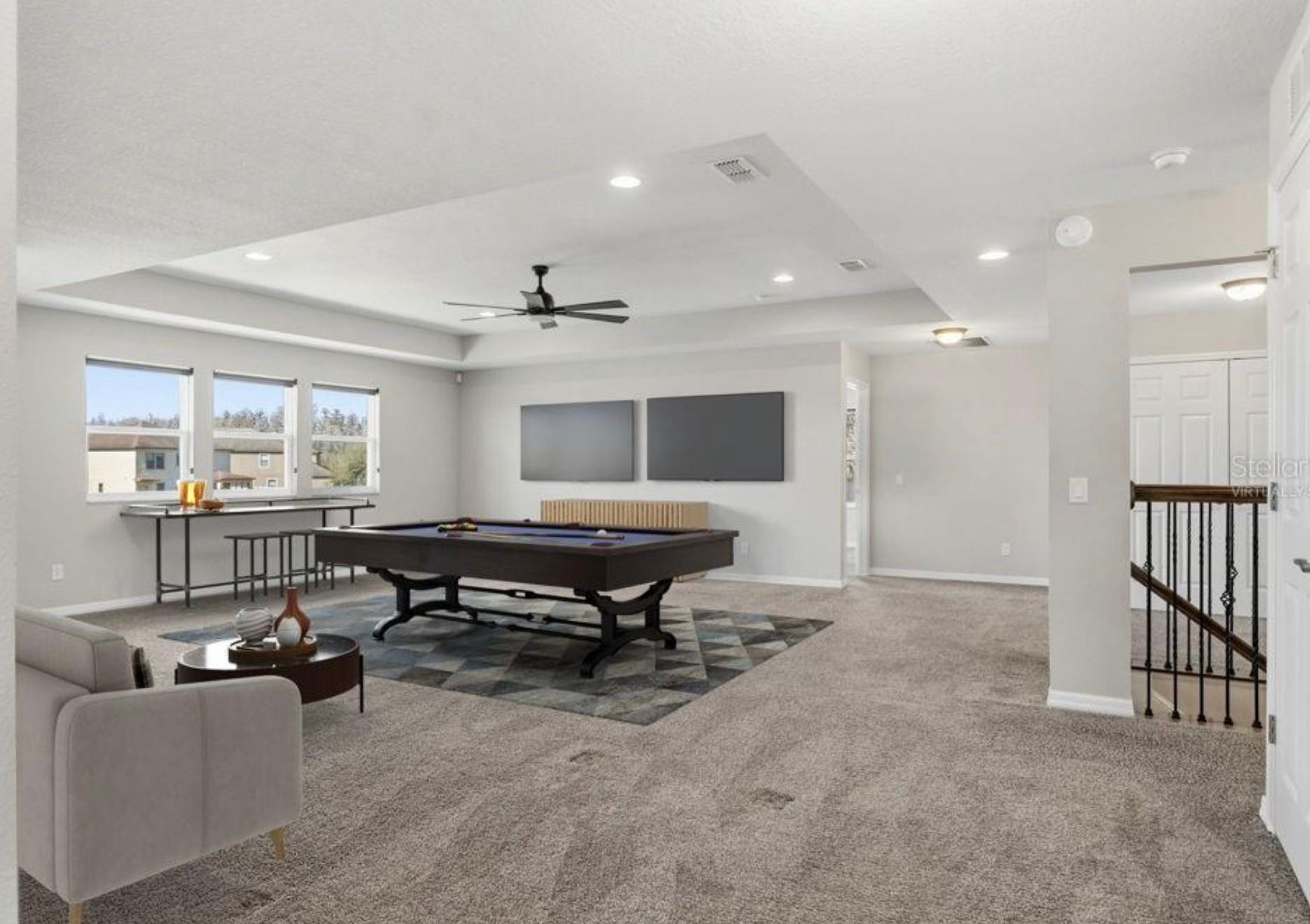 Spacious game room with a pool table, two TVs, and a seating area.