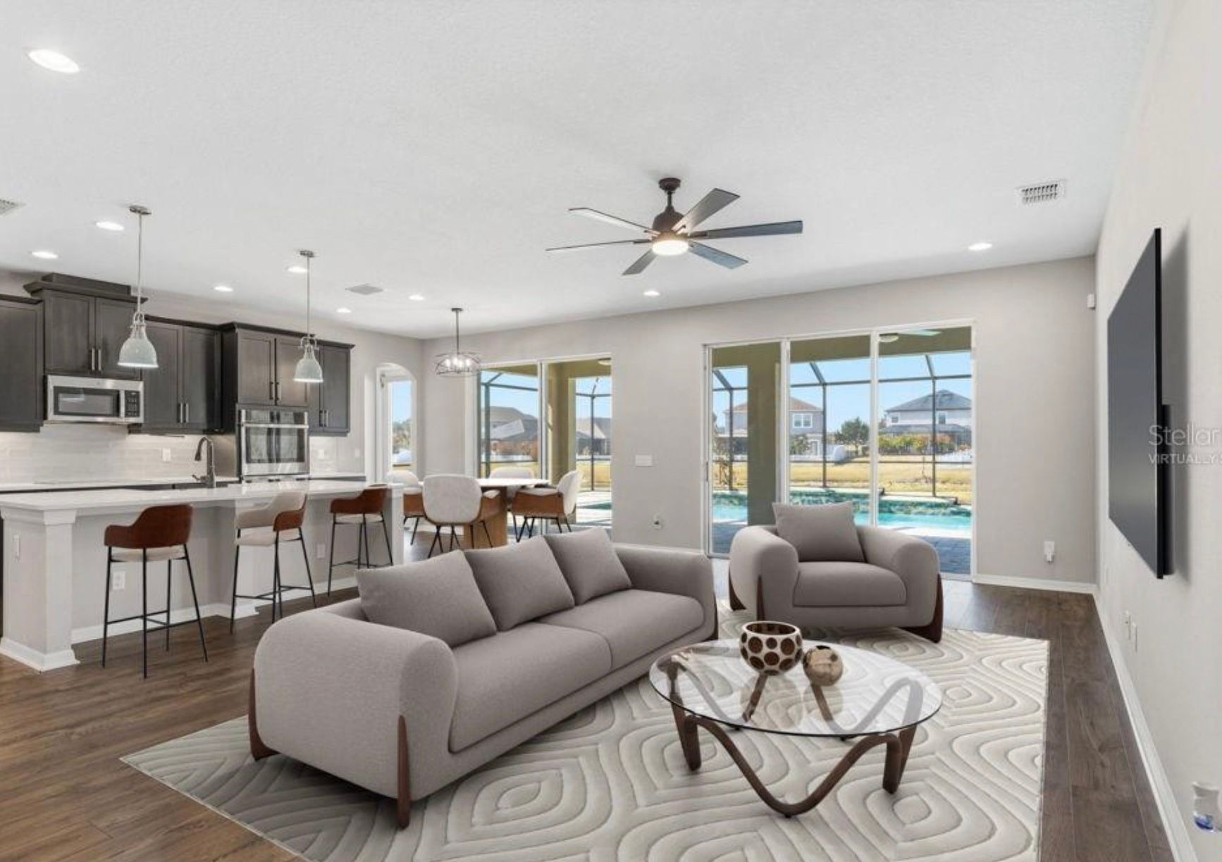 Open-concept living space with kitchen, living room, and pool view through sliding glass doors.