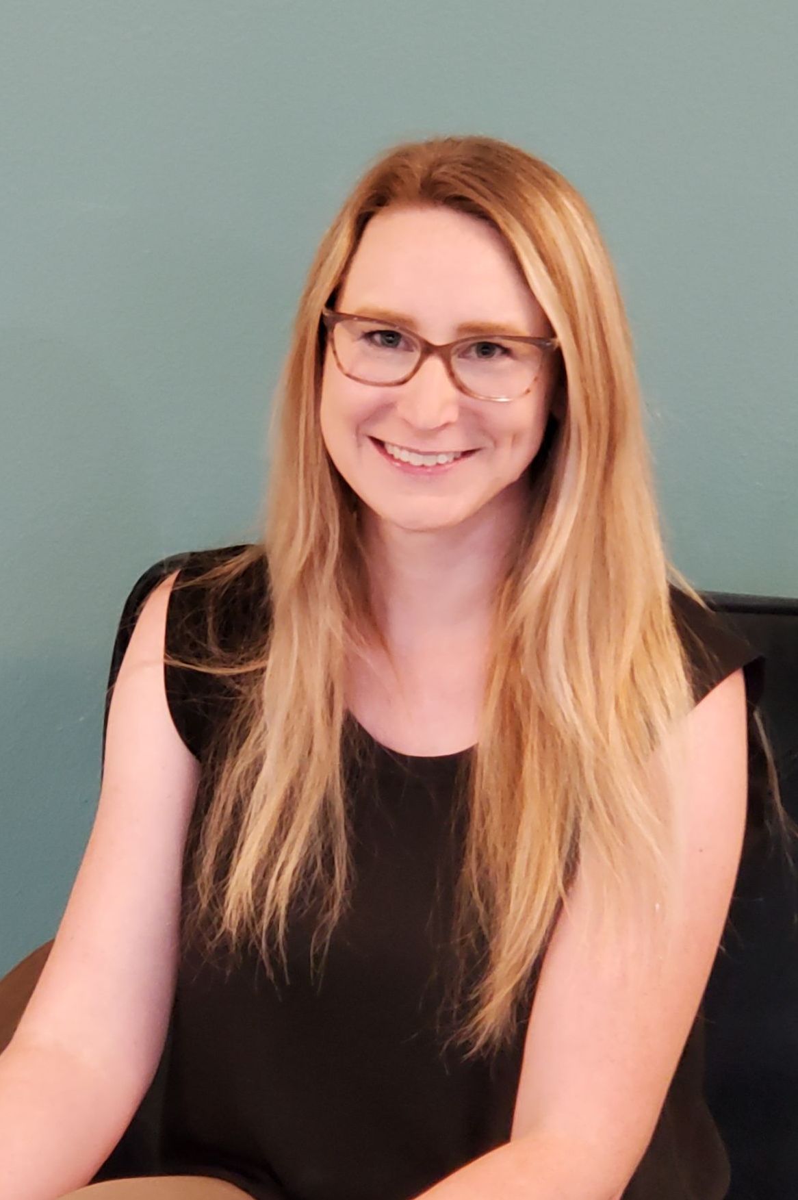 a woman in a dark tank top and blond hair smiling 