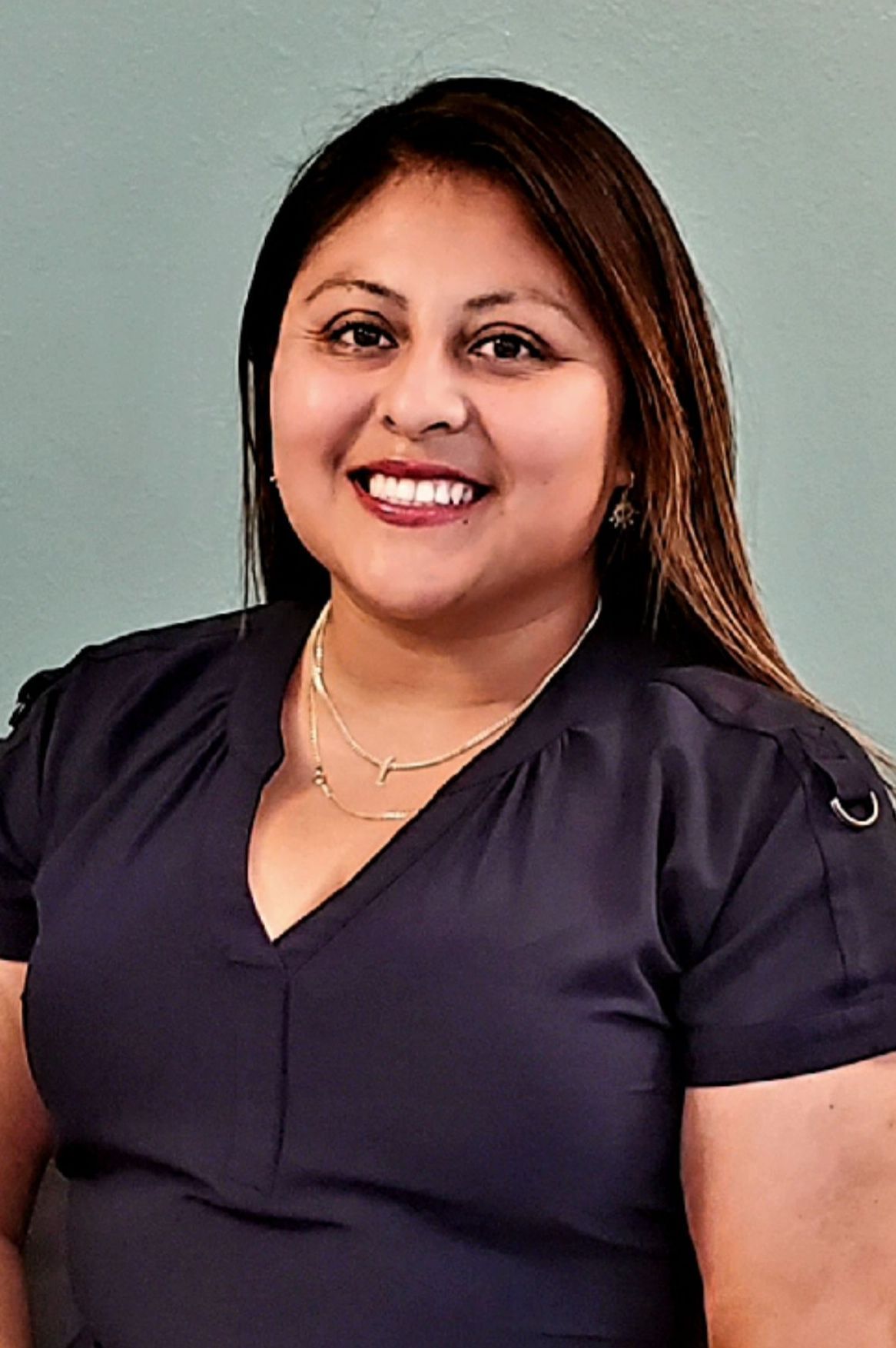 a woman sitting in a chair with dark hair and dark dress and a big smile