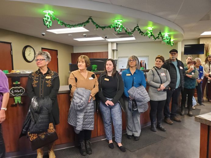 A group of people are standing in front of a counter in a bank.