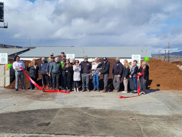 A group of people are standing in front of a pile of mulch.