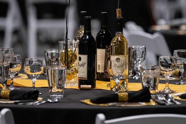 A table set for a dinner party with wine bottles and glasses on it.