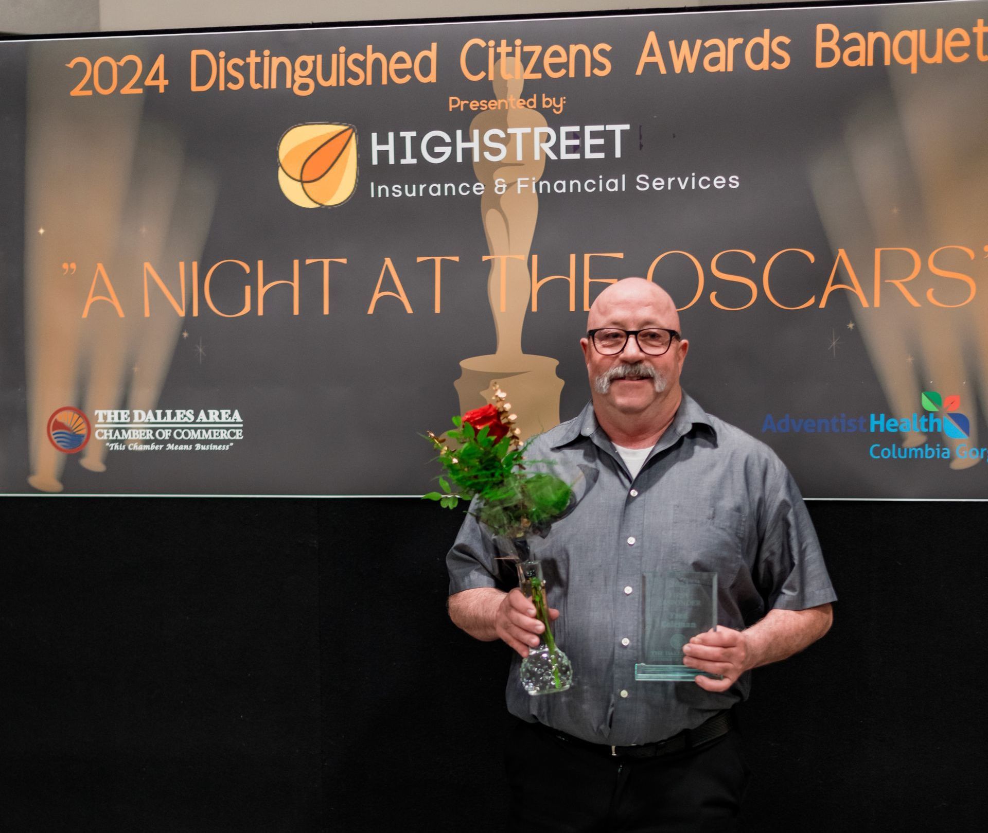 A man in front of a sign that says 2024 distinguished citizens awards banquet