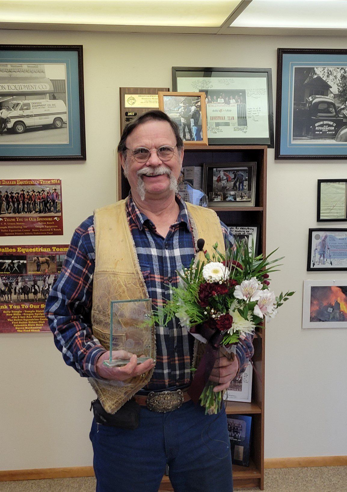 A man is holding a bouquet of flowers and a trophy.