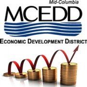 A logo for the mid-columbia economic development district with stacks of coins and an arrow.