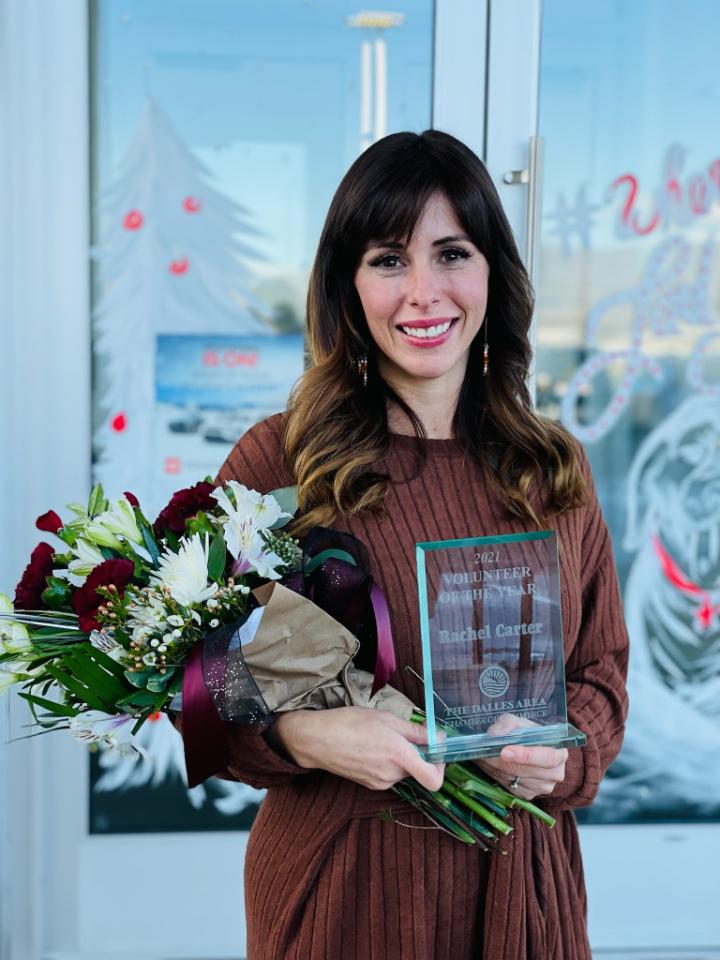 A woman is holding a trophy and a bouquet of flowers.