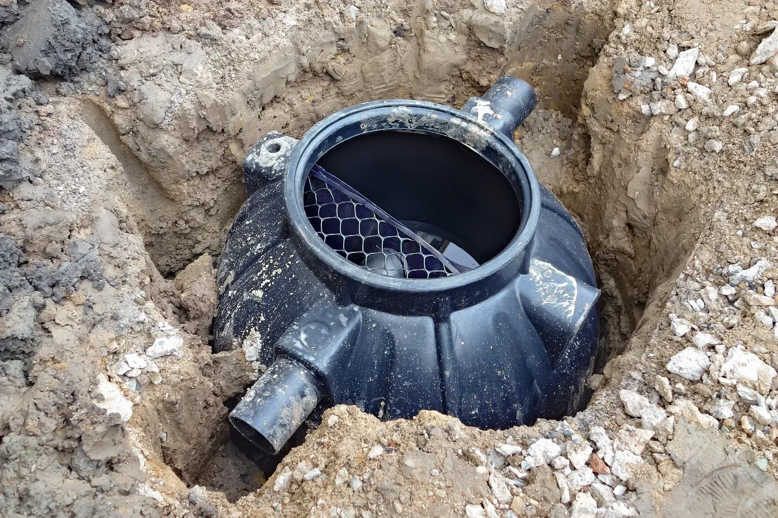 Black plastic underground pipe chamber in a dirt excavation pit