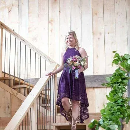 Woman in purple lace dress descends wooden stairs