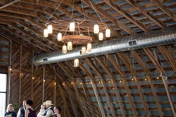 Barn interior with a rustic chandelier and wedding guests