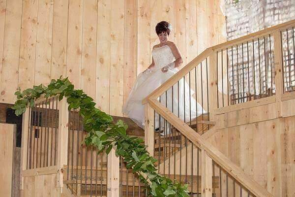 Bride in white dress descending wooden stairs