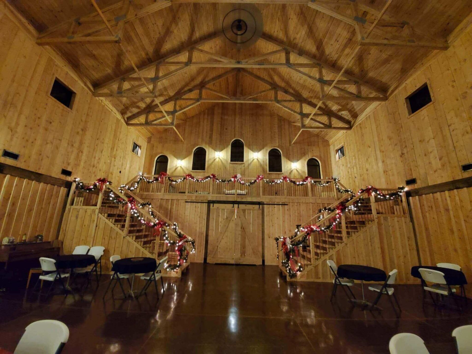 Interior of a wooden barn with a balcony and staircases decorated with garland
