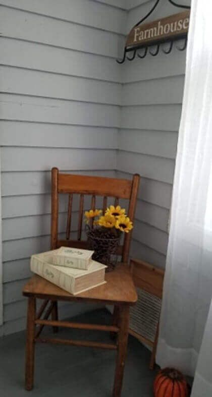 Wooden chair on porch, with books, sunflowers, and 