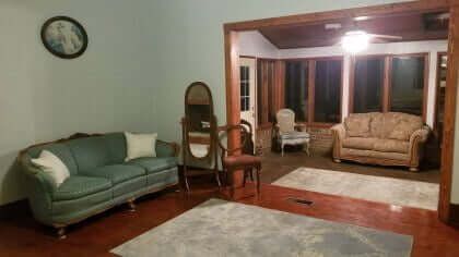 Living room with green and beige couches, rug, mirror, and picture.
