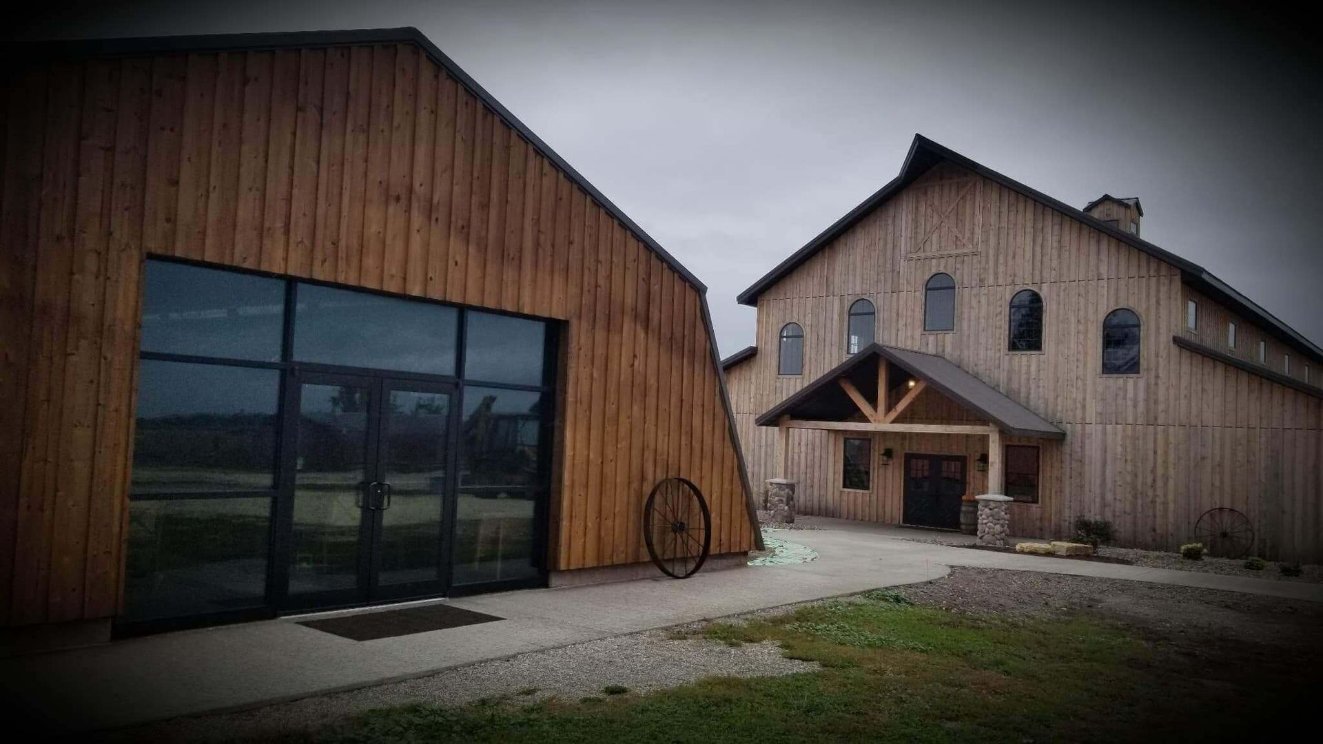 Wooden barn-style event venue with large glass doors and an arched entryway under a cloudy sky
