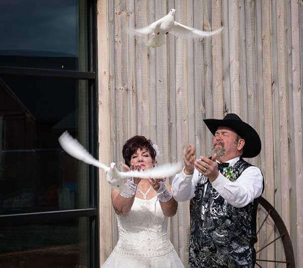 Bride and groom release white doves during outdoor wedding ceremony.