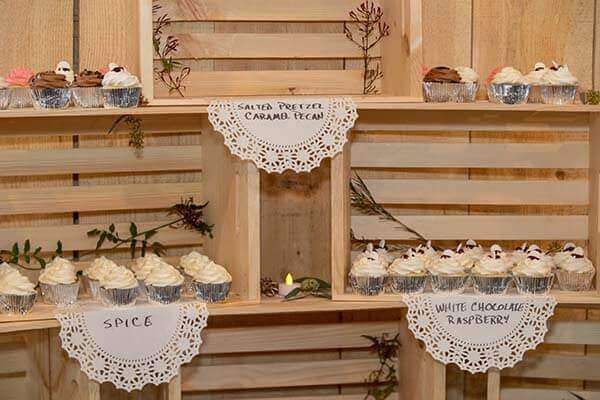 Cupcake display with wooden crates, white doilies, and various cupcake flavors.