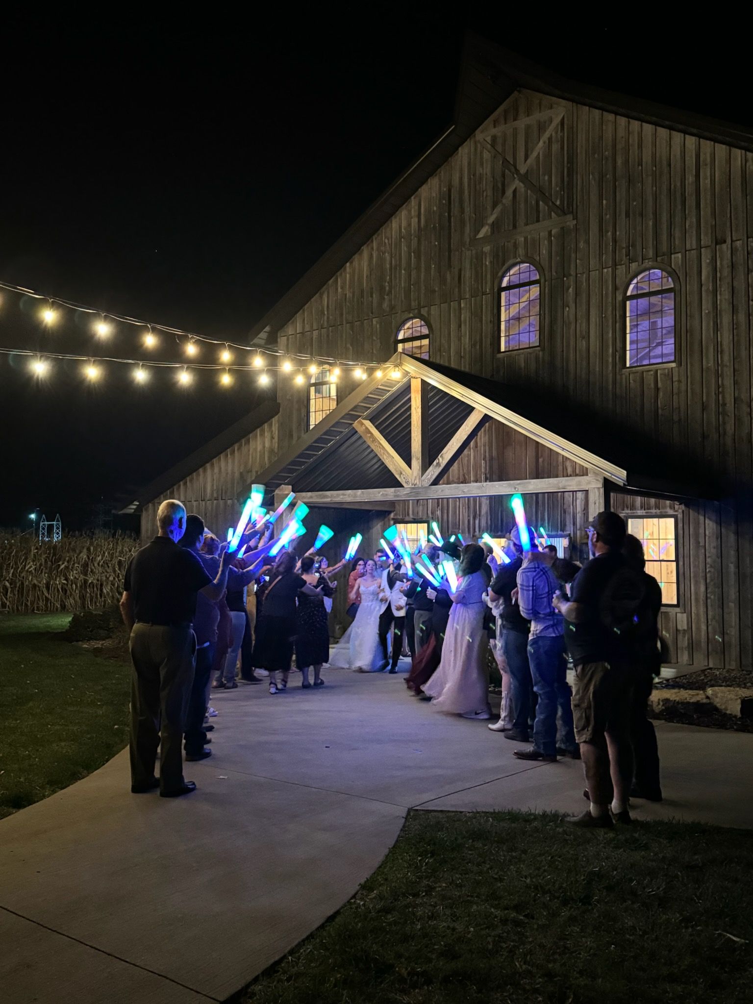 People with glowing lights celebrate outside a barn at night.