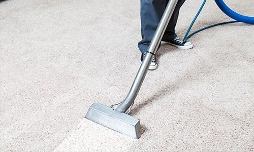 Una persona está usando una aspiradora para limpiar una alfombra.