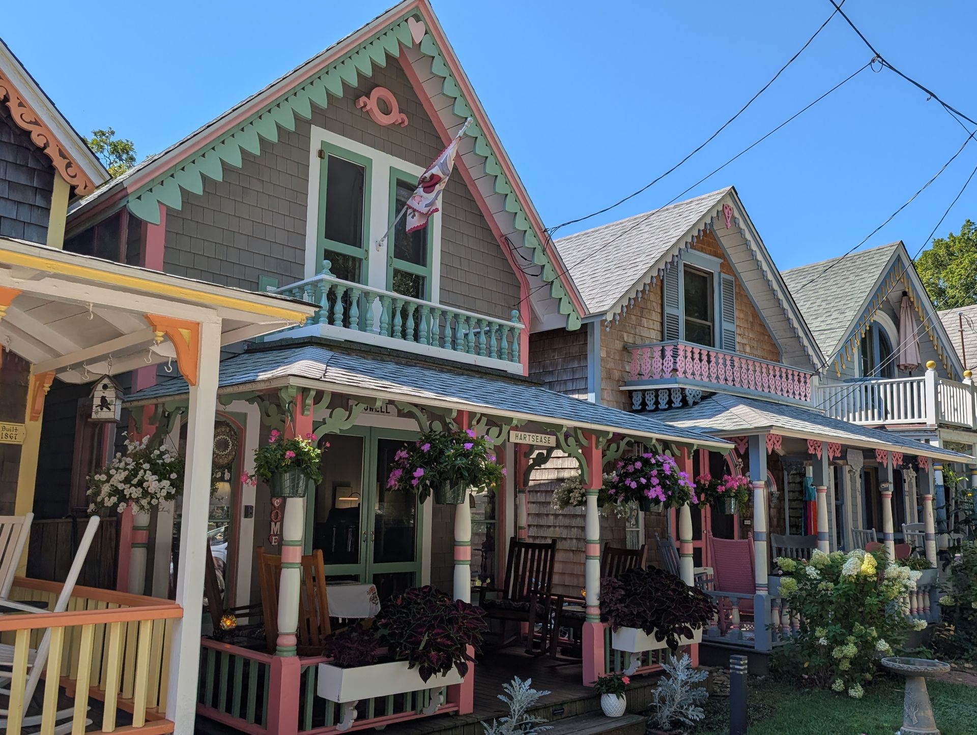 Quaint, colorful gingerbread cottages with decorative trim and porches arranged in a row under a clear blue sky.