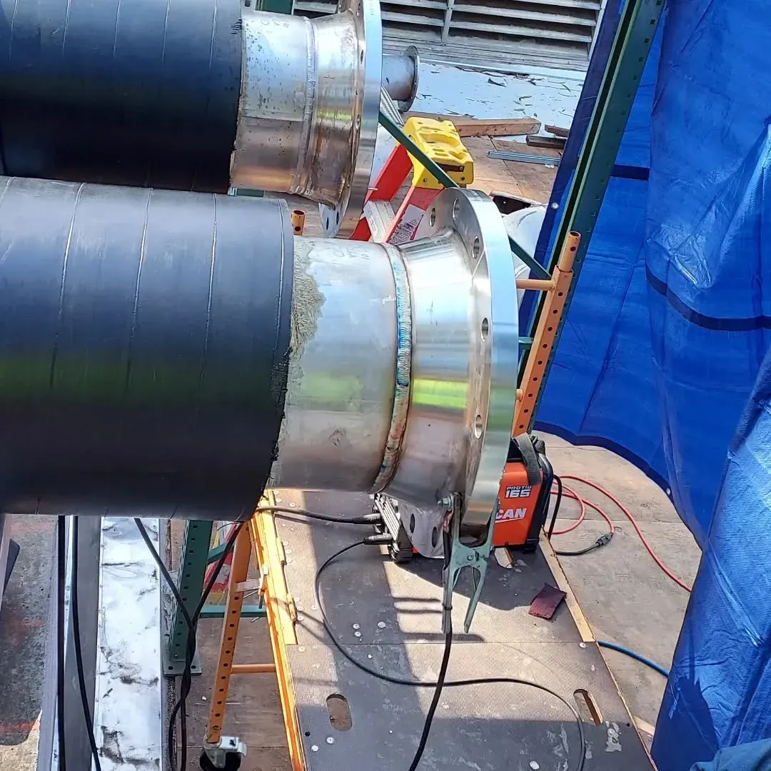 A person is working on a pipe with a blue tarp in the background
