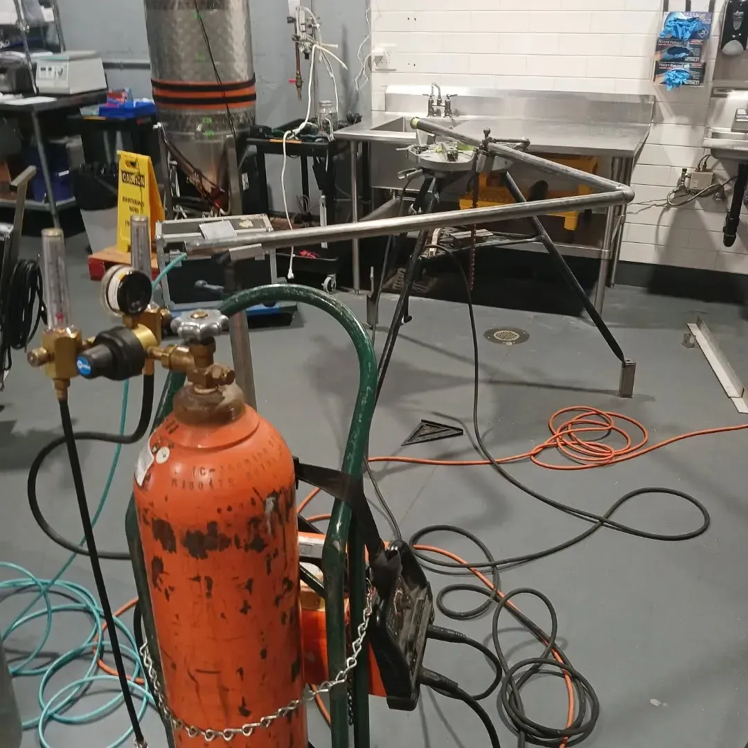 An orange gas cylinder is sitting in a messy room
