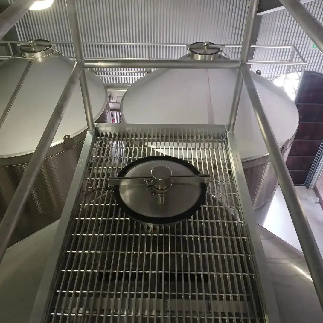A row of stainless steel tanks are sitting on top of a metal grate.