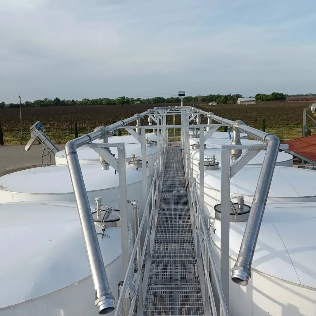 A metal walkway leading to a row of white tanks