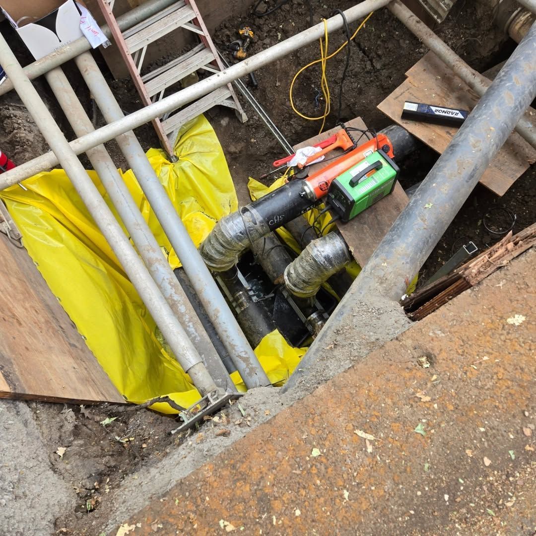 A bunch of pipes are being worked on in the dirt