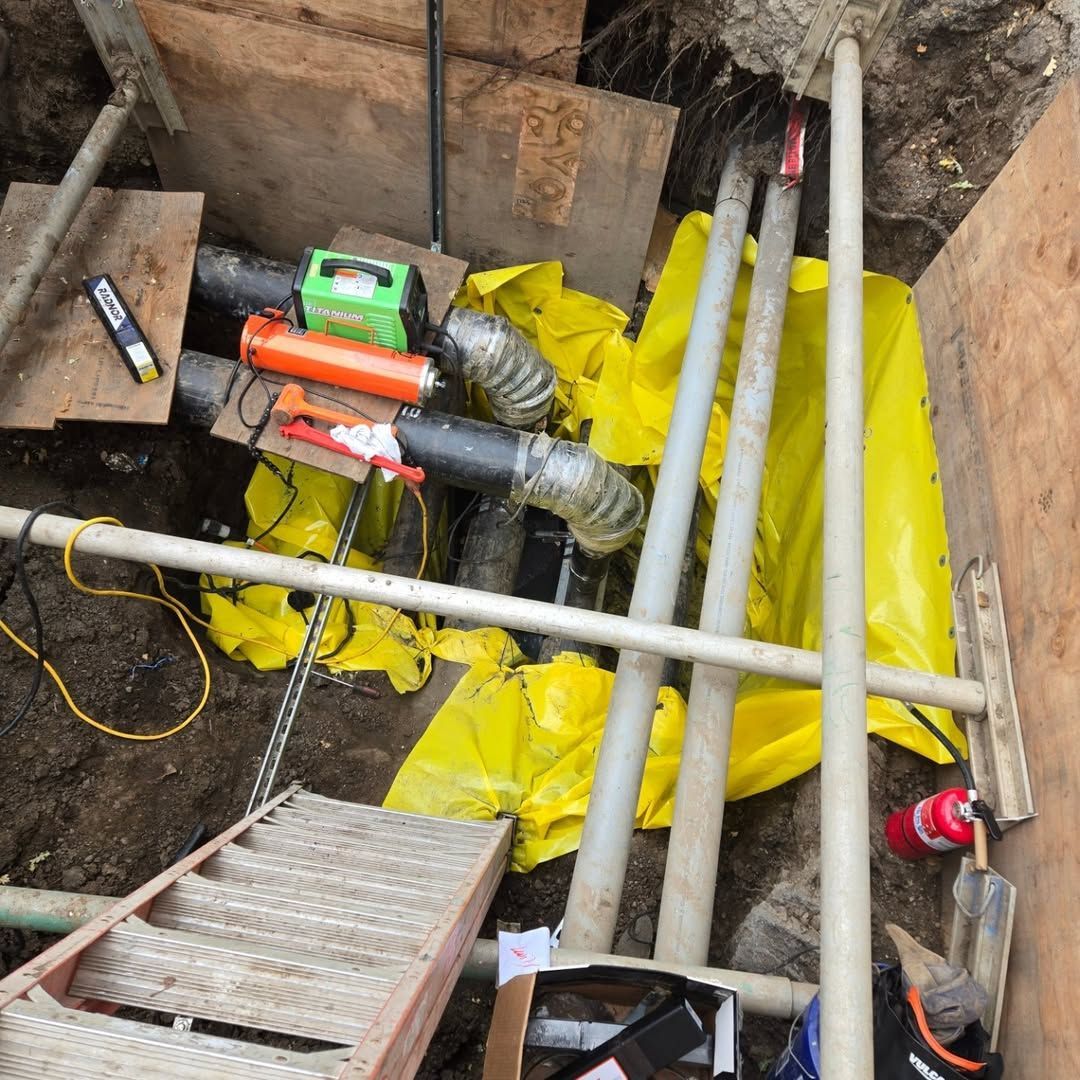 A bunch of pipes and a ladder in a hole