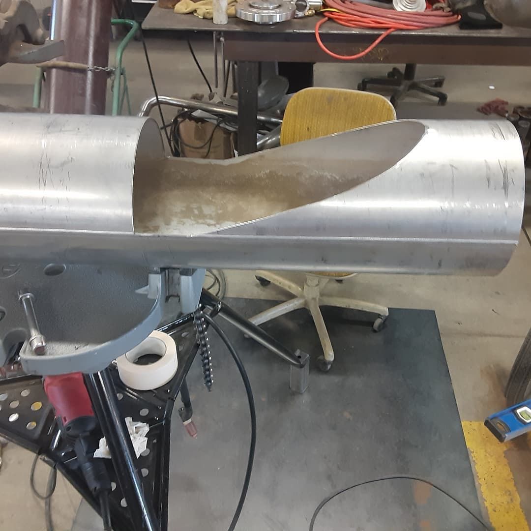 A large metal pipe is sitting on a table in a workshop