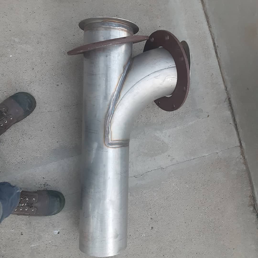 A metal pipe is sitting on the ground next to a person 's feet.