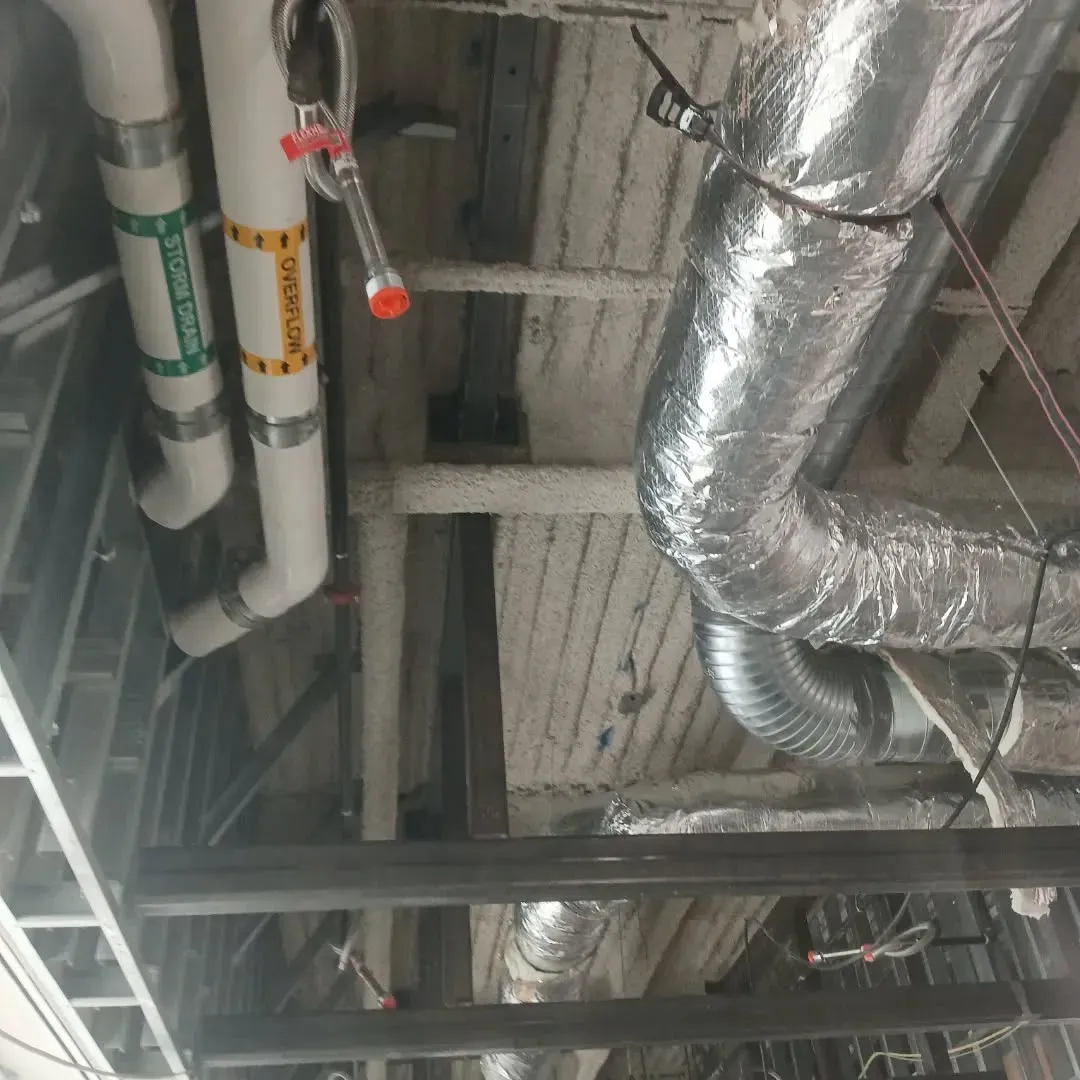 A bunch of pipes are hanging from the ceiling in a building