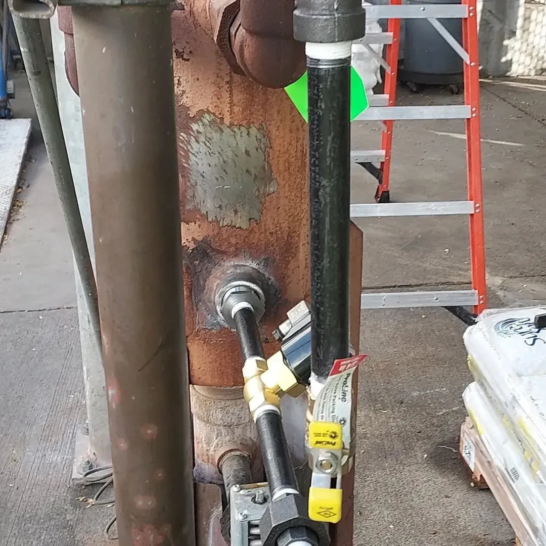 A ladder is next to a pipe with a green tag that says ' a ' on it