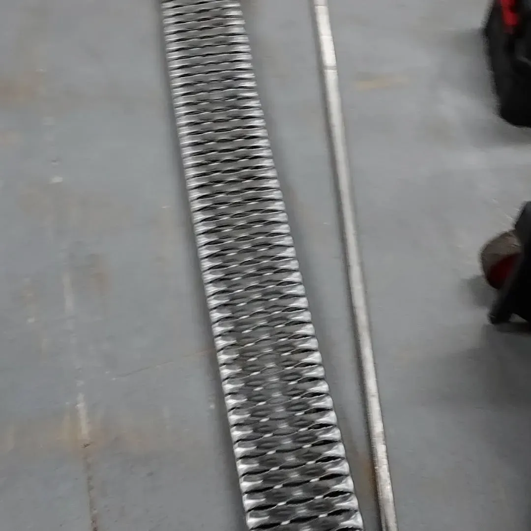 A metal grate is sitting on a concrete floor next to a metal pole.