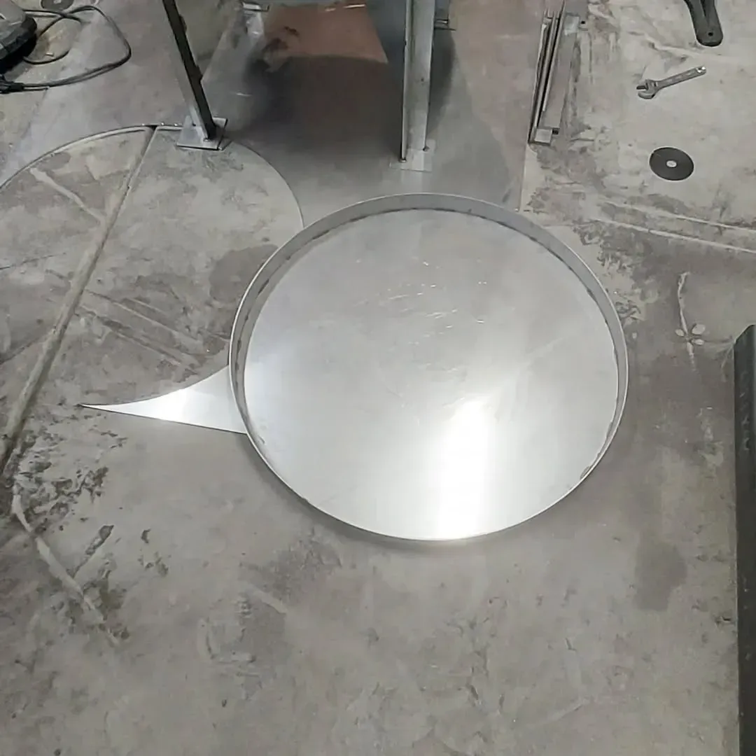 A round metal object is sitting on a concrete floor.