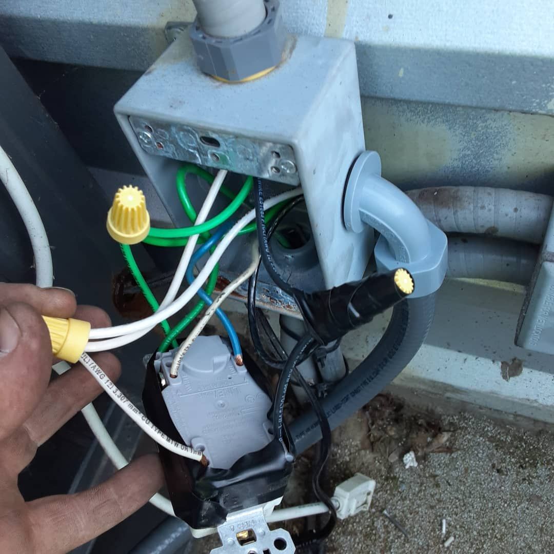 A hand is reaching into a box with wires coming out of it