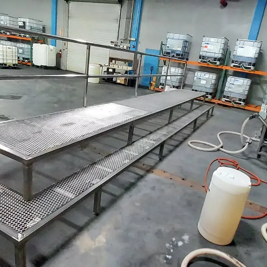 A stainless steel ramp is in a warehouse next to a bucket